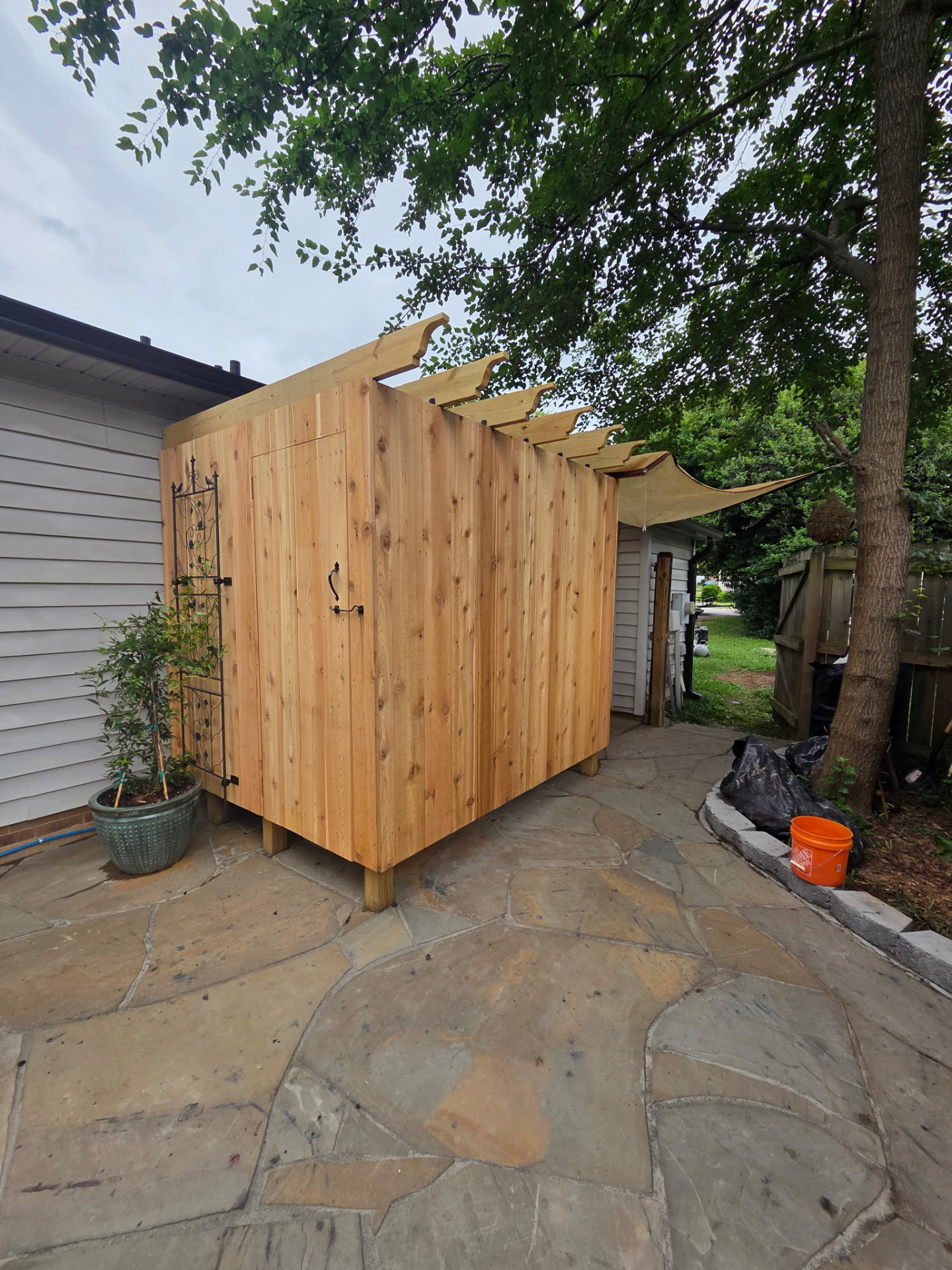 Custom cedar outdoor shower enclosure with pergola over a flagstone patio